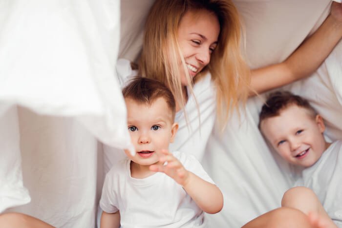 Mother and her two sons playing under a blanket
