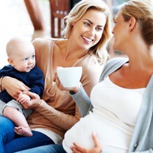 Happy pregnant woman with her friends relaxing at home