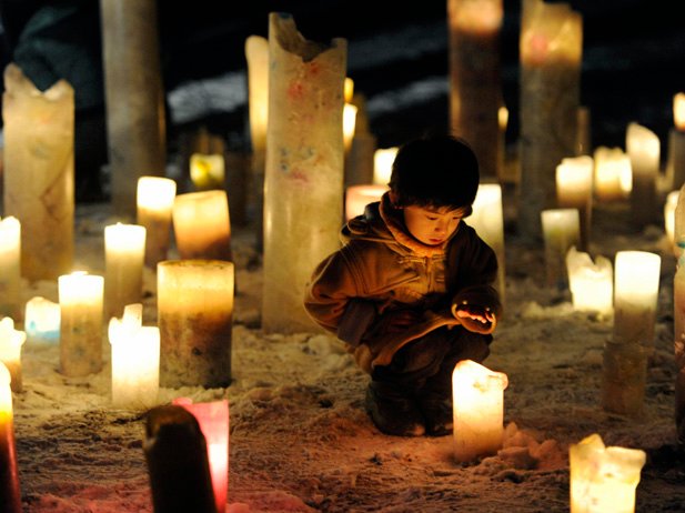 A child looks at a candle flame during an event to pray for the reconstruction of areas devastated by the March 11, 2011 earthquake and tsunami, in Iwanuma in Miyagi prefecture, an area hit by the disaster, in this photo taken by Kyodo January 11, 2012.  Mandatory Credit REUTERS/Kyodo 

(JAPAN - Tags: DISASTER SOCIETY) FOR EDITORIAL USE ONLY. NOT FOR SALE FOR MARKETING OR ADVERTISING CAMPAIGNS. THIS IMAGE HAS BEEN SUPPLIED BY A THIRD PARTY. IT IS DISTRIBUTED, EXACTLY AS RECEIVED BY REUTERS, AS A SERVICE TO CLIENTS. MANDATORY CREDIT. JAPAN OUT. NO COMMERCIAL OR EDITORIAL SALES IN JAPAN