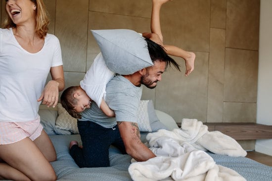 Family playing together on bed at home. Little boy playing with his parents in bedroom.