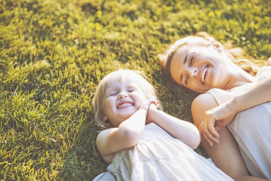 smiling mother and baby laying on meadow