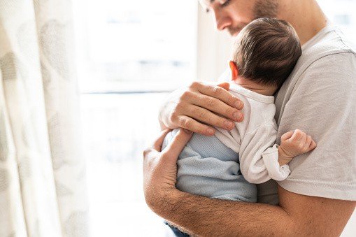 Affectionate love between father and newborn baby, father holding his son in arms in apartment